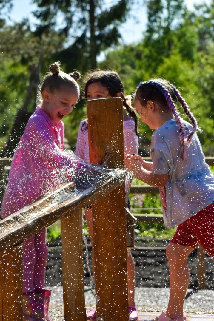A group of friends around a hand activated water pump